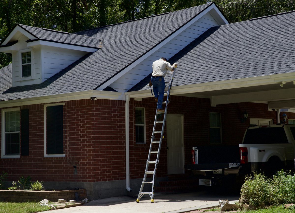 Trophy Exteriors inspector climbing a ladder to inspect a shingle roof